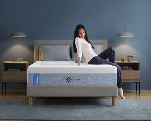 A woman sitting on a Zinus Cooling Green Tea Memory Foam Mattress, featuring cooling gel and pressure relief for better sleep.